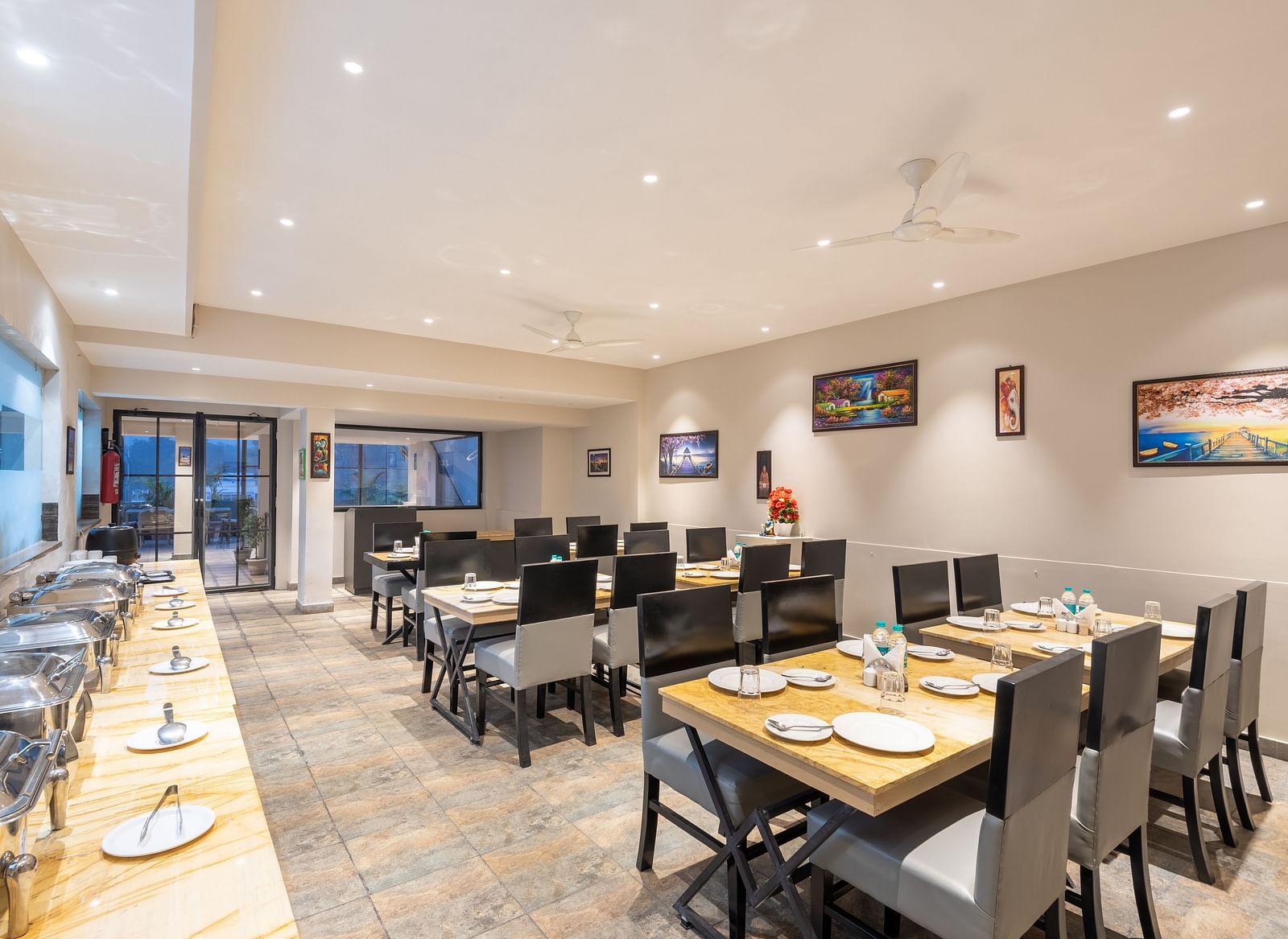 The indoor restaurant set up with chairs and tables along with a buffet table on the left at DLS Hotel Arihant, Haridwar