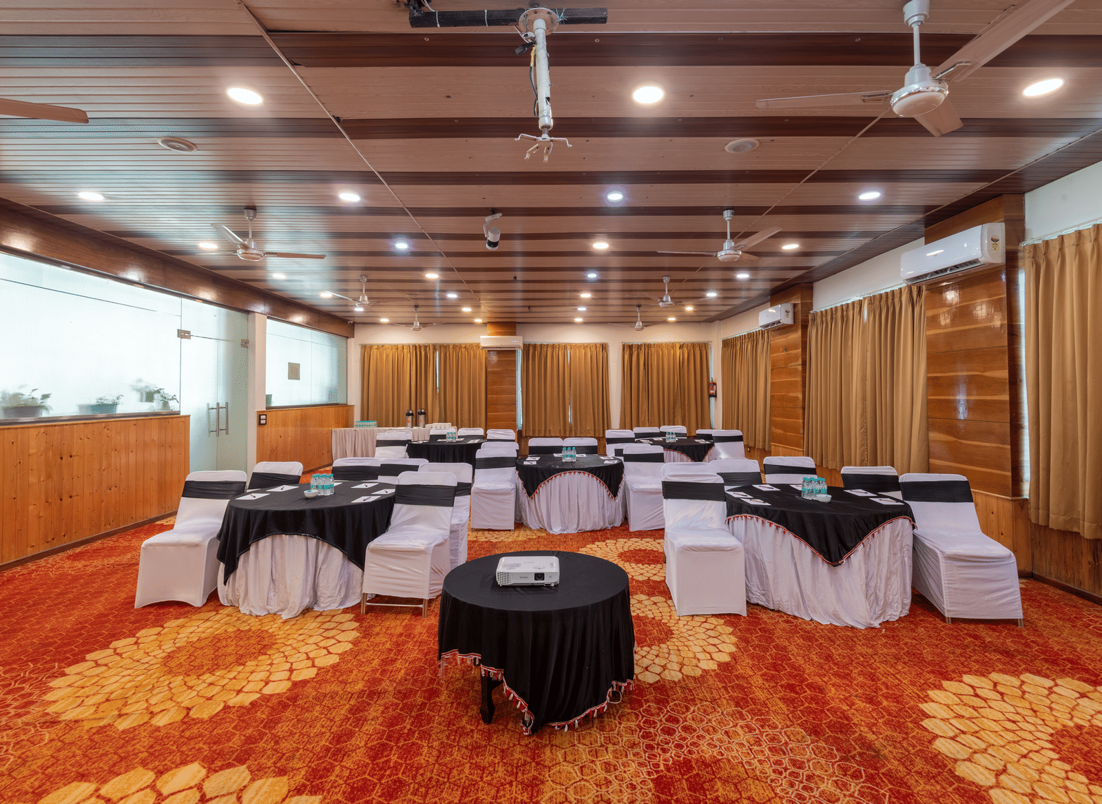A large conference style hall at DLS Hotels on the Ganges Rishikesh with ample seating soft lighting and a wide layout crafted to host professional events group discussions and medium sized gatherings.