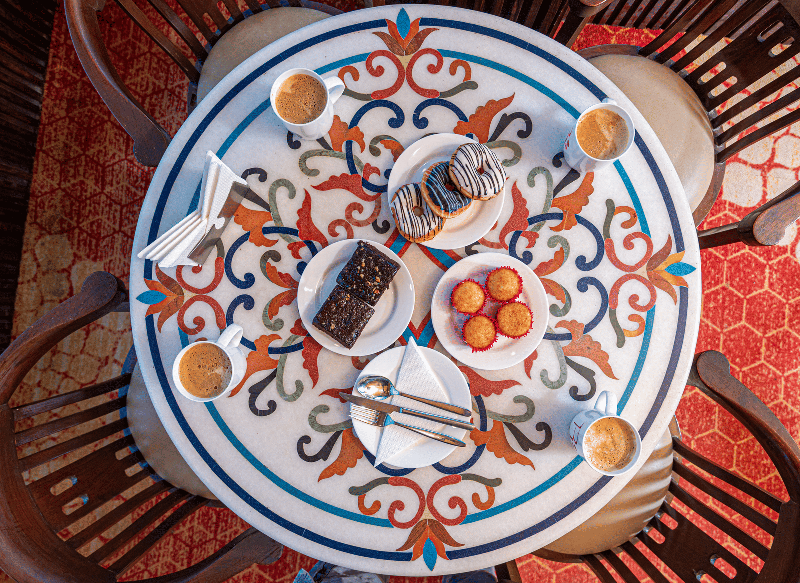 A detailed dining table setup at DLS Hotels on the Ganges Rishikesh showcasing an assortment of fresh dishes elegantly arranged on a patterned table with scenic hill views creating a warm and inviting meal experience.