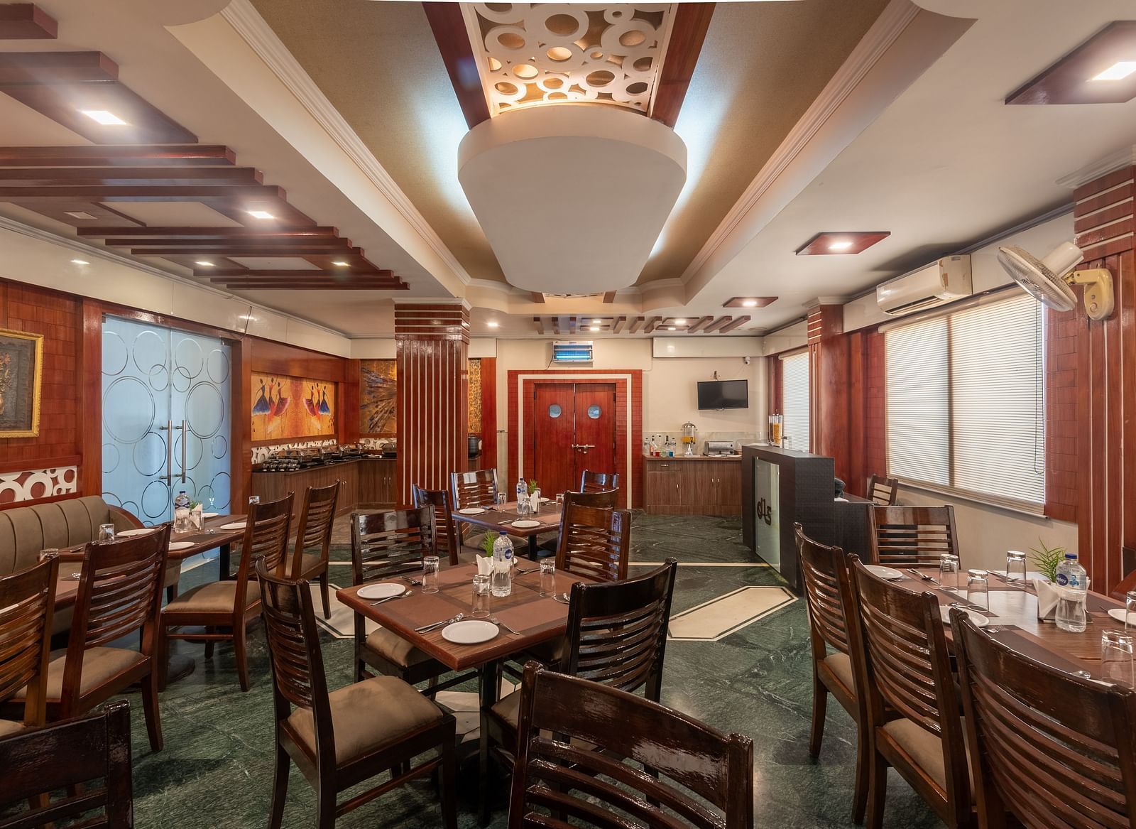 Dining area with a designed ceiling and wooden tables and chairs at DLS Park Grace, Haridwar.