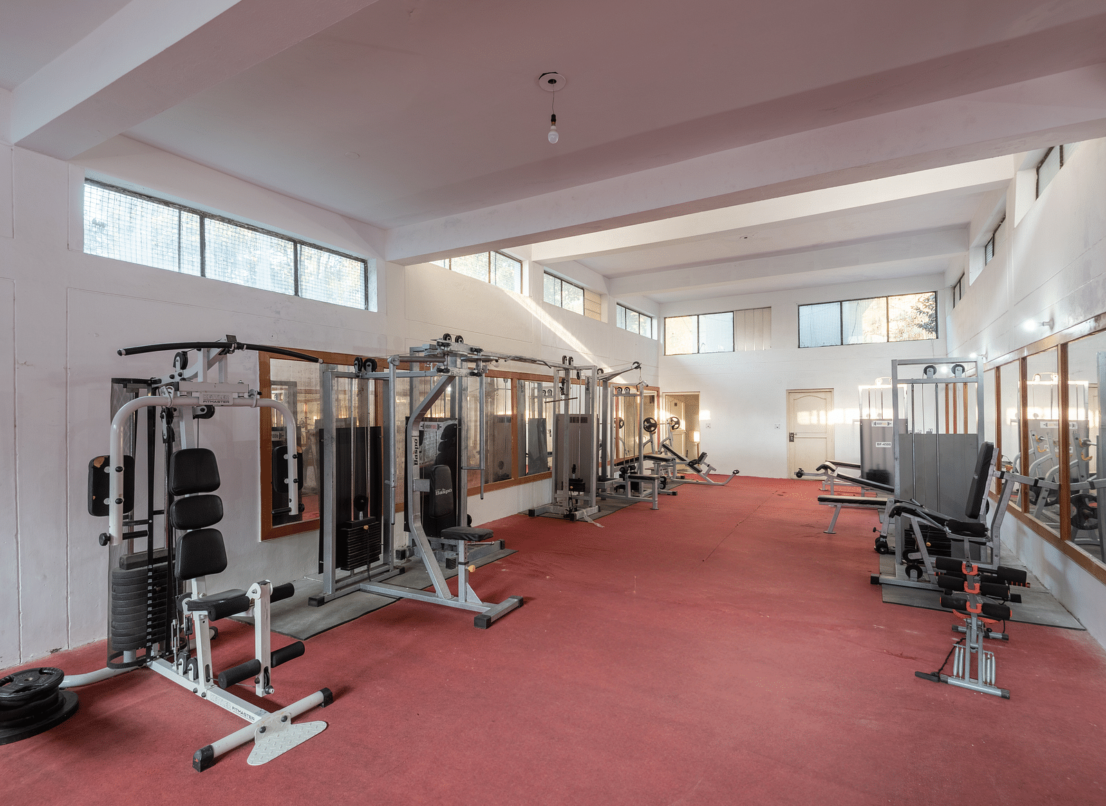 A well-equipped gym at DLS Tehri Club Resort with a variety of cardio and strength training equipment.