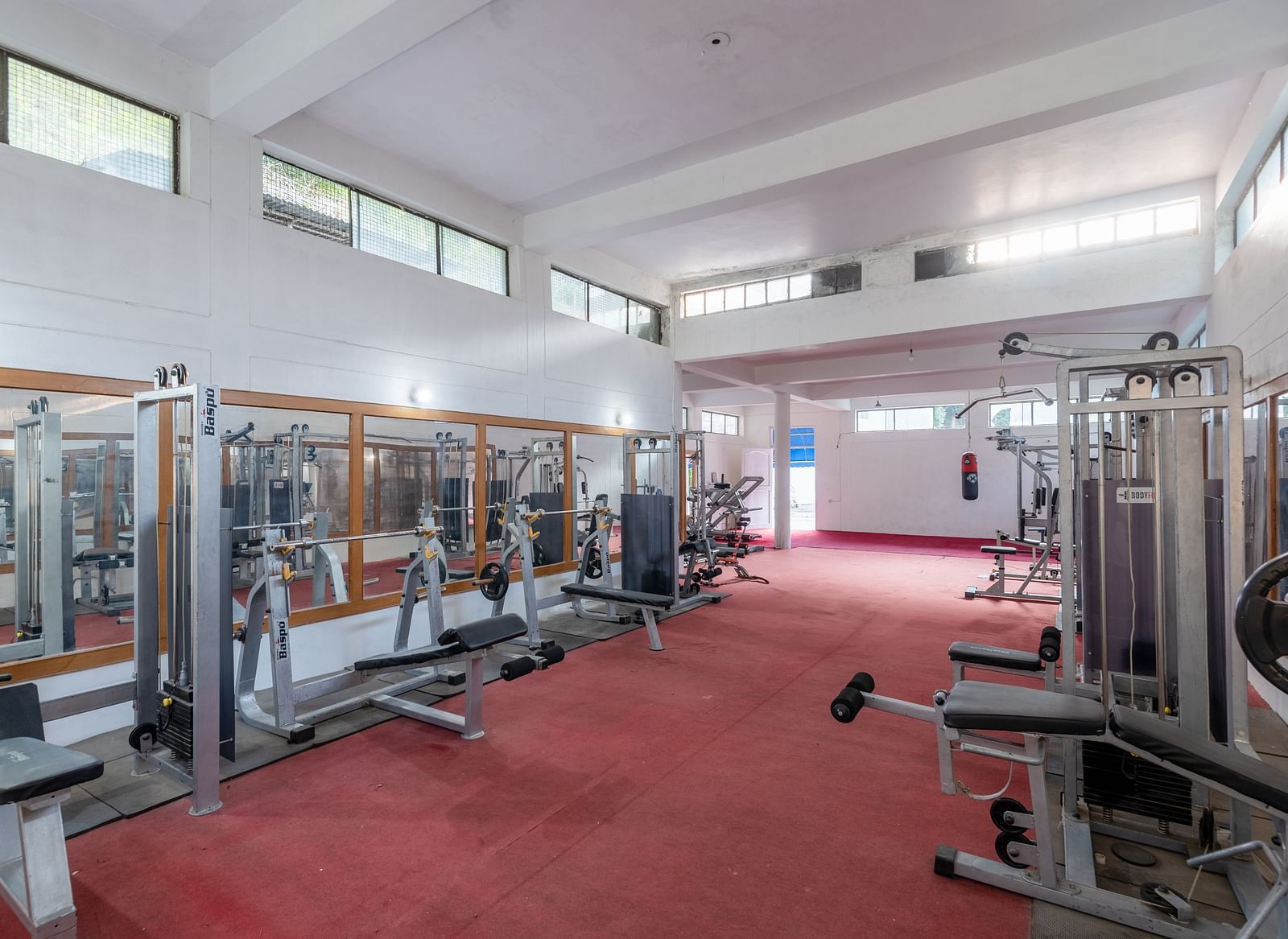 A spacious and well-lit gym at DLS Tehri Club Resort, offering a variety of equipment for a full workout.