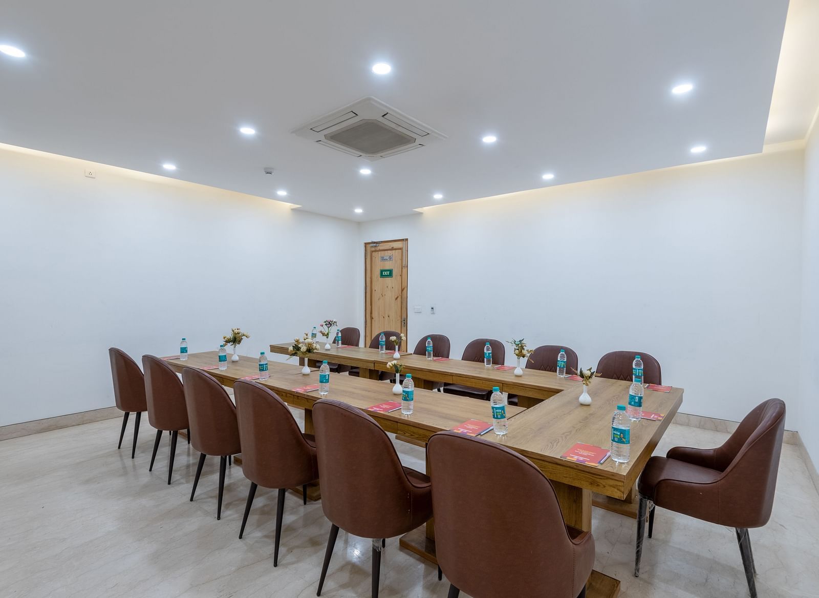 Side view of a conference room with multiple chairs, an air conditioner, and water bottles placed on the table at DLS The Classio