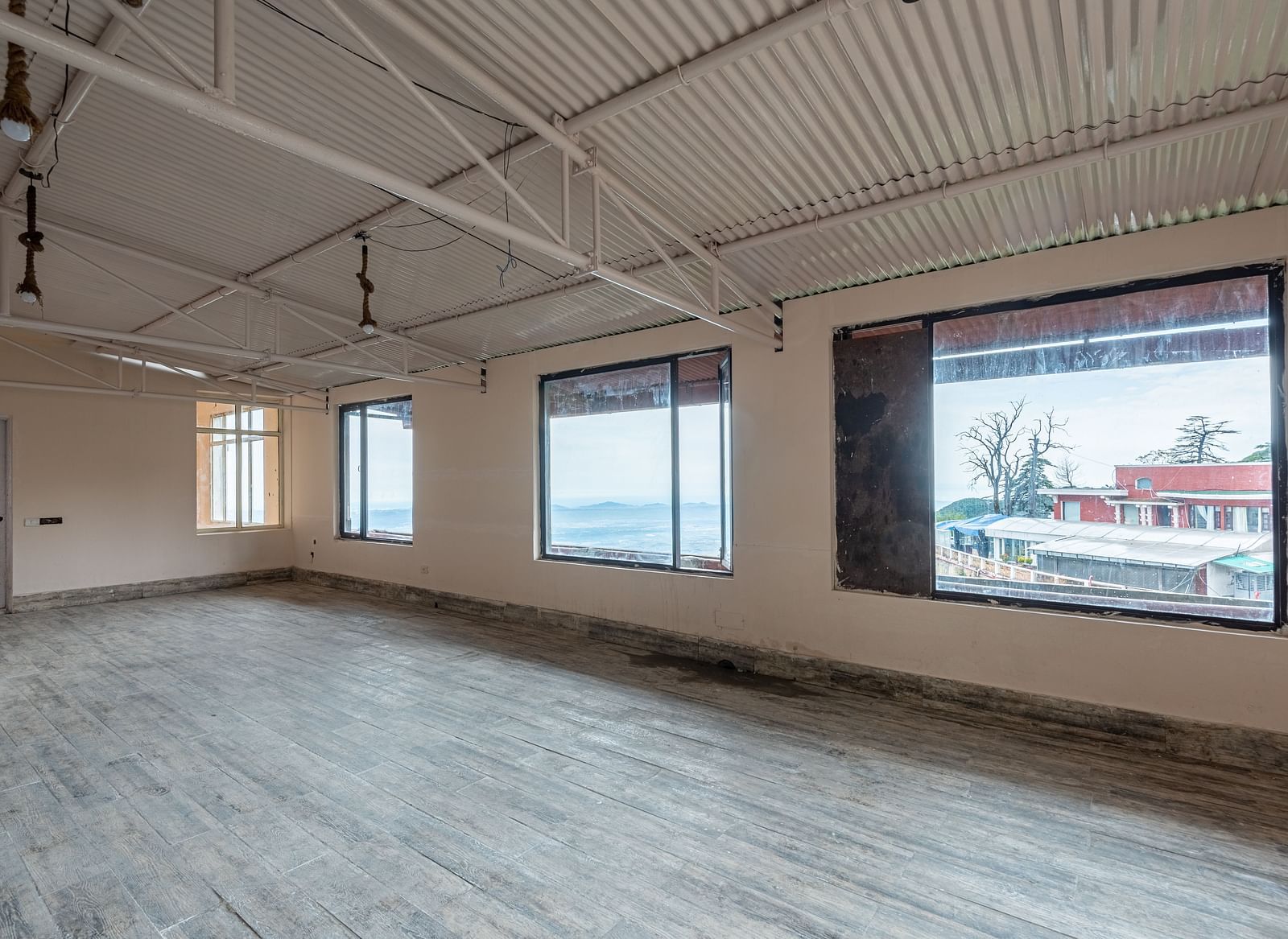 A large, empty room with high ceilings and several large windows offering views of the outdoors | DLS The Pearl