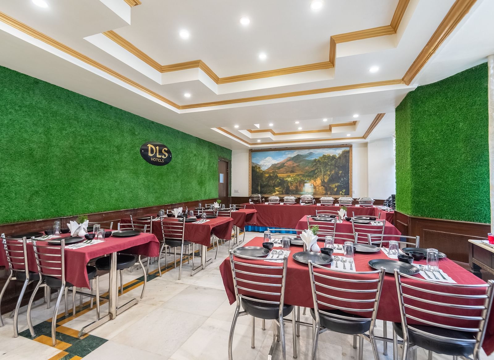 A spacious restaurant with a green wall, red tablecloths, and a scenic mural on one wall | DLS The Pearl