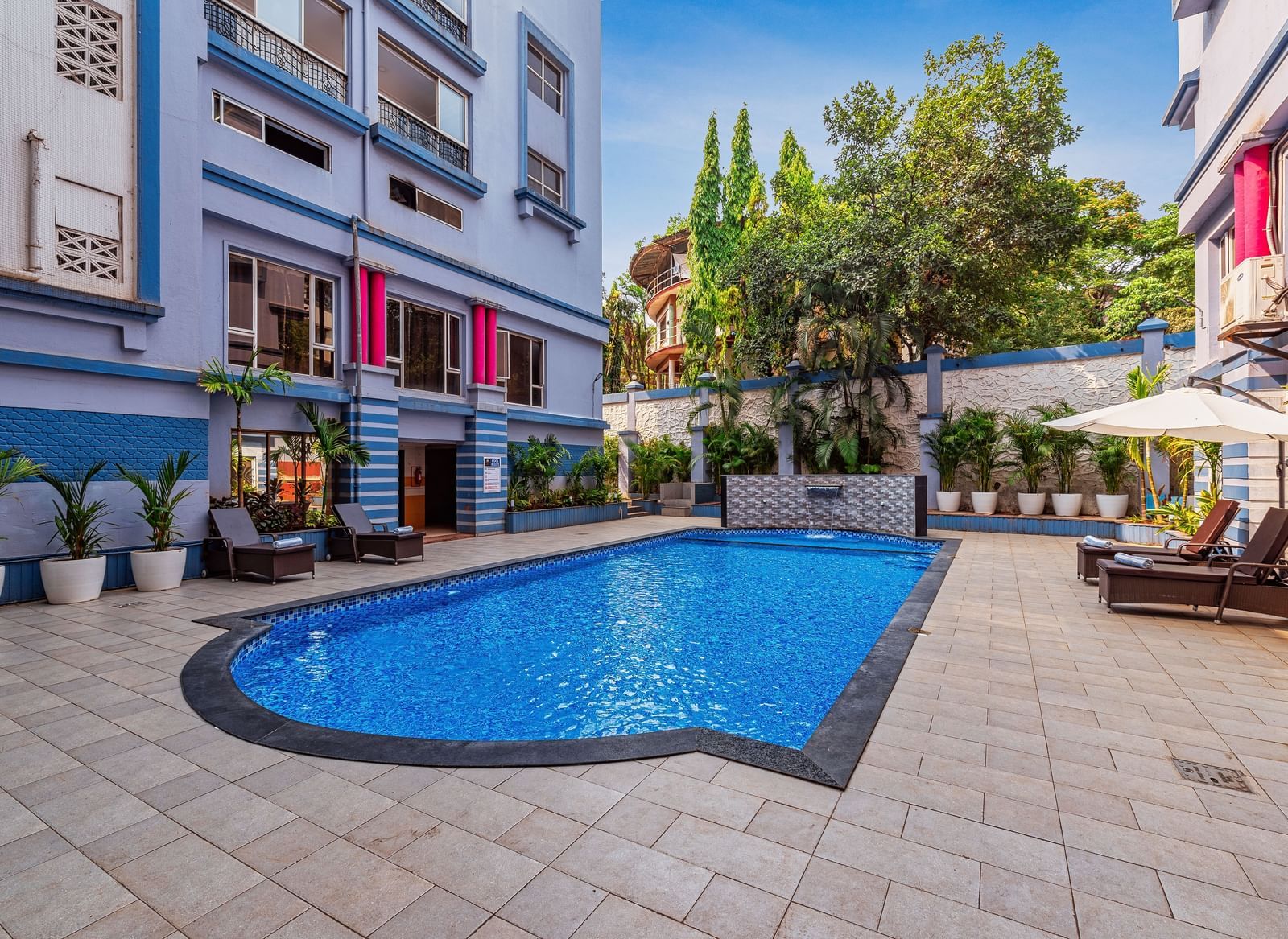 Outdoor swimming pool surrounded by the resort’s vibrant buildings, with poolside seating and lush greenery creating a refreshing leisure space.