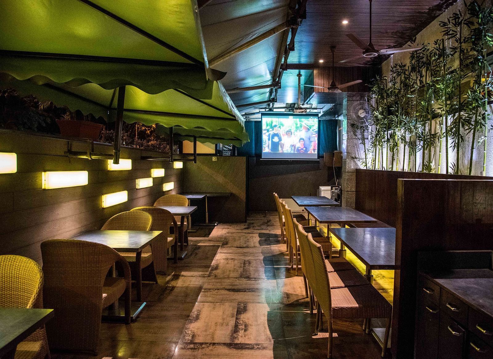 Modern restaurant featuring wooden chairs, tables, and a wall with plants hanging as decoration at Oriental Aster, Mumbai.