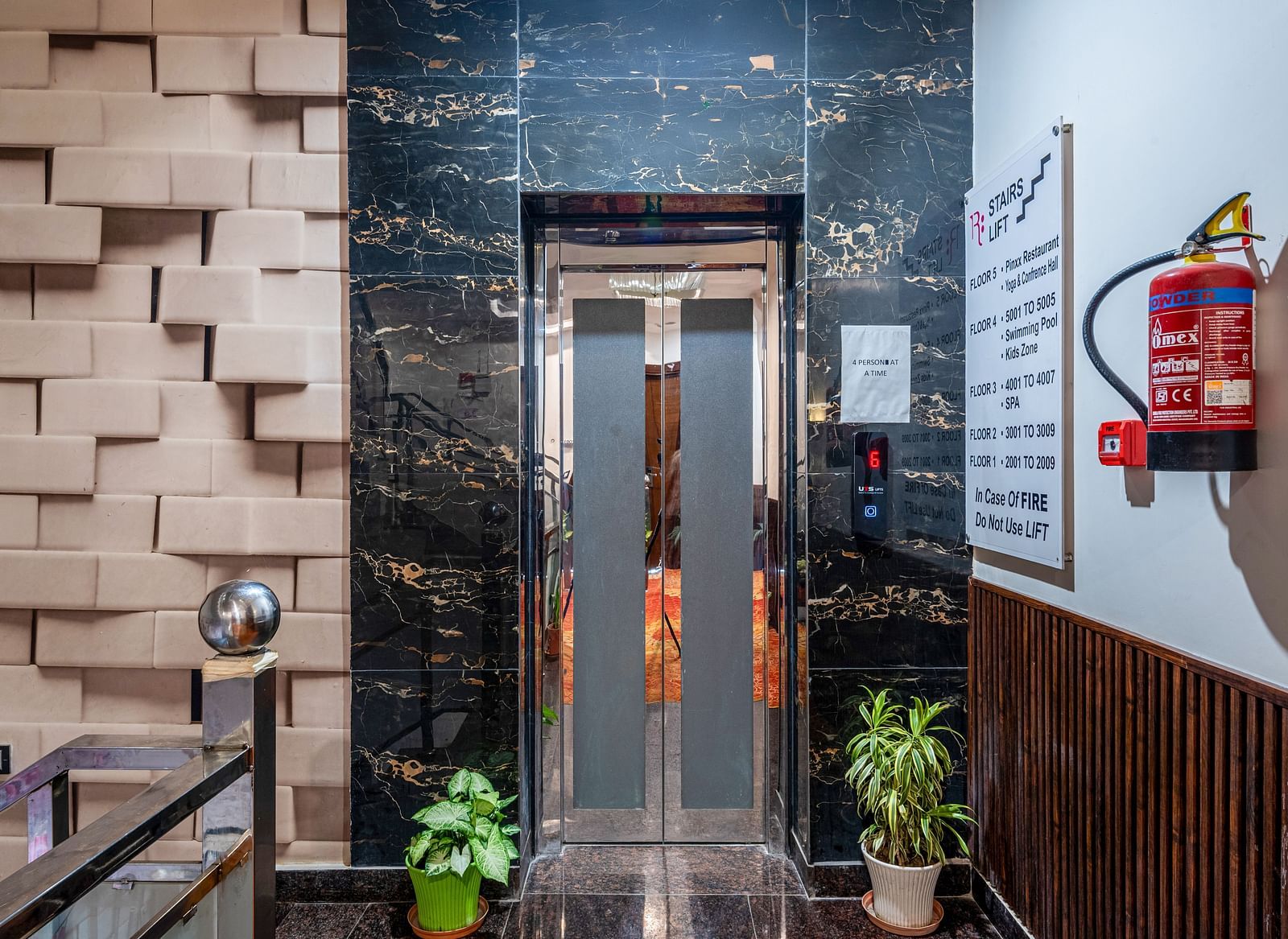 Lift at Regenta Inn DLS, Rishikesh with potted plants and a fire extinguisher.