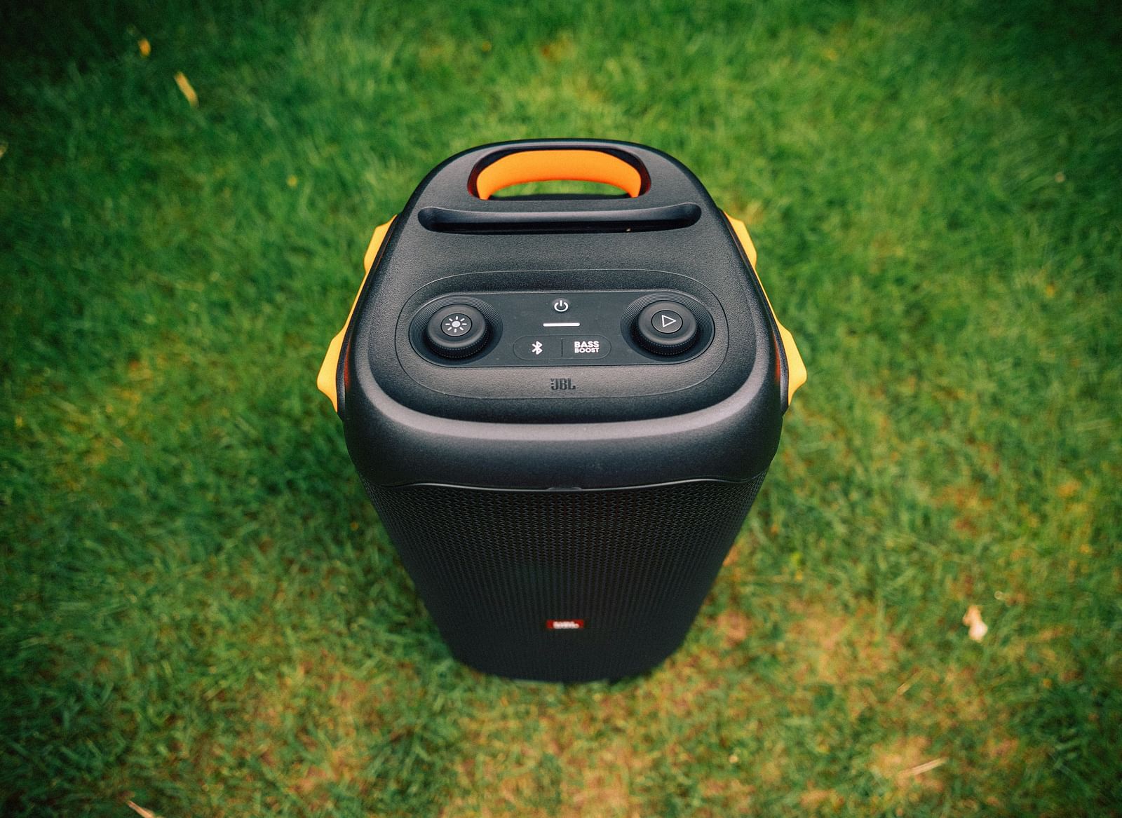 Black portable Bluetooth speaker placed on the grass.