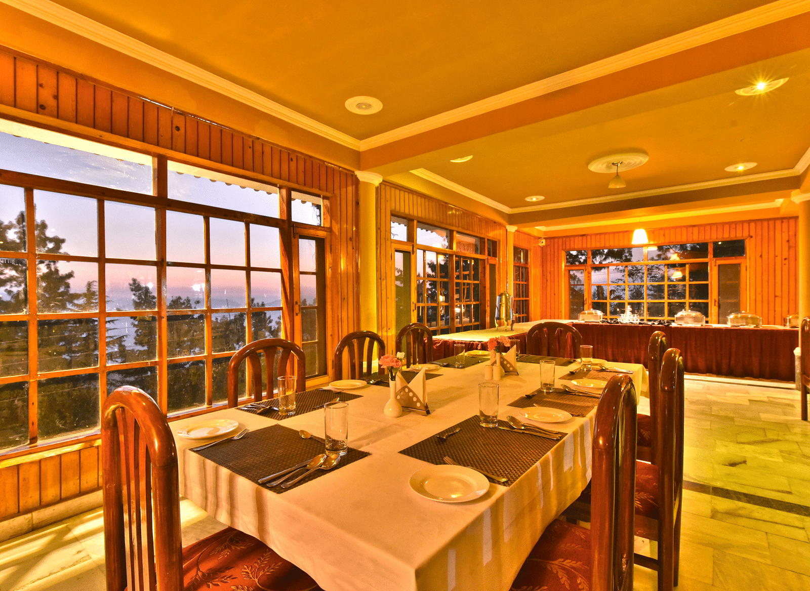 Restaurant with large windows offering scenic views at DLS Hillcrest Resort, Shimla.