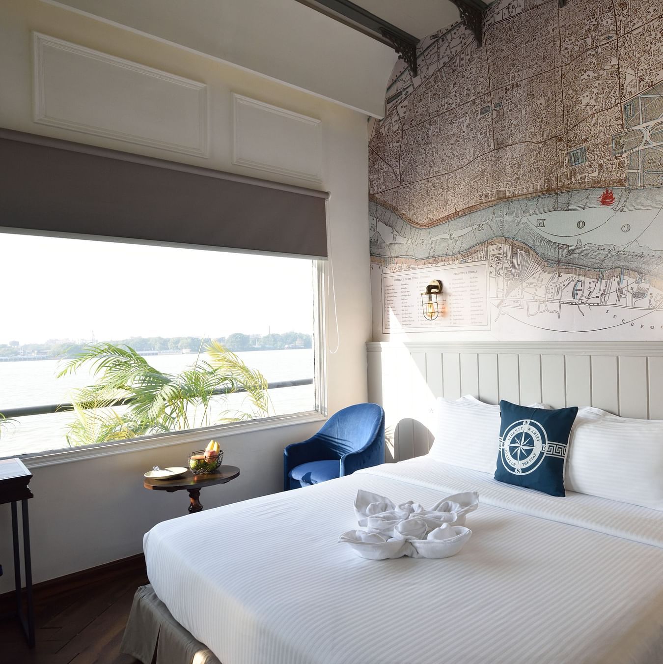 a well made bed with blue pillows and a lamp hanging above the bed - polo floatel kolkata