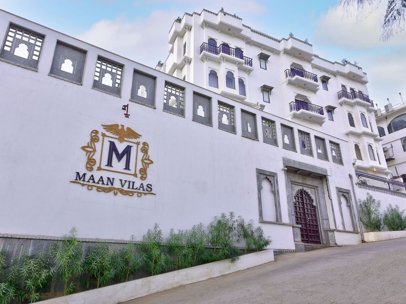 white coloured entrance of the hotel with mewar style architecture and plants outside Maan Vilas by Stonewood 