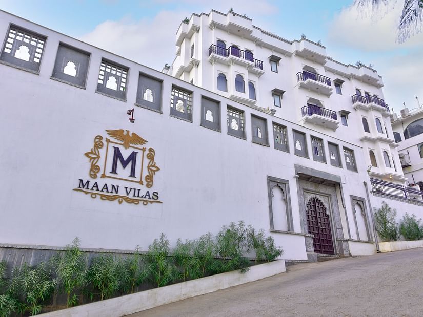 white coloured entrance of the hotel with mewar style architecture and plants outside Maan Vilas by Stonewood 