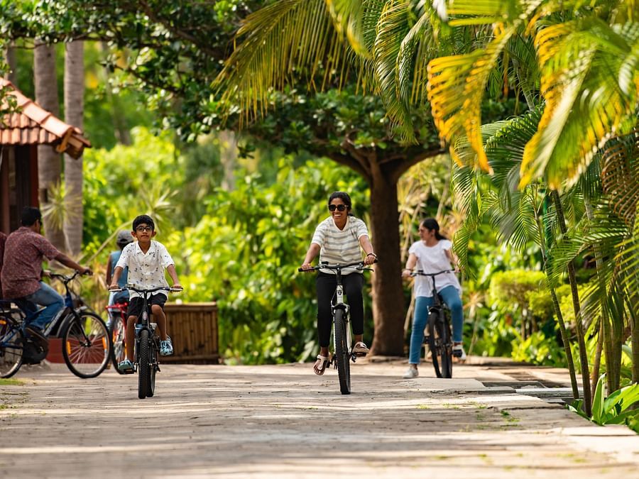 a group of kids cycling on a stone pathway with trees surrounding it and it is one of the best things to do in Pollachi - Ibex River Resort, Pollachi