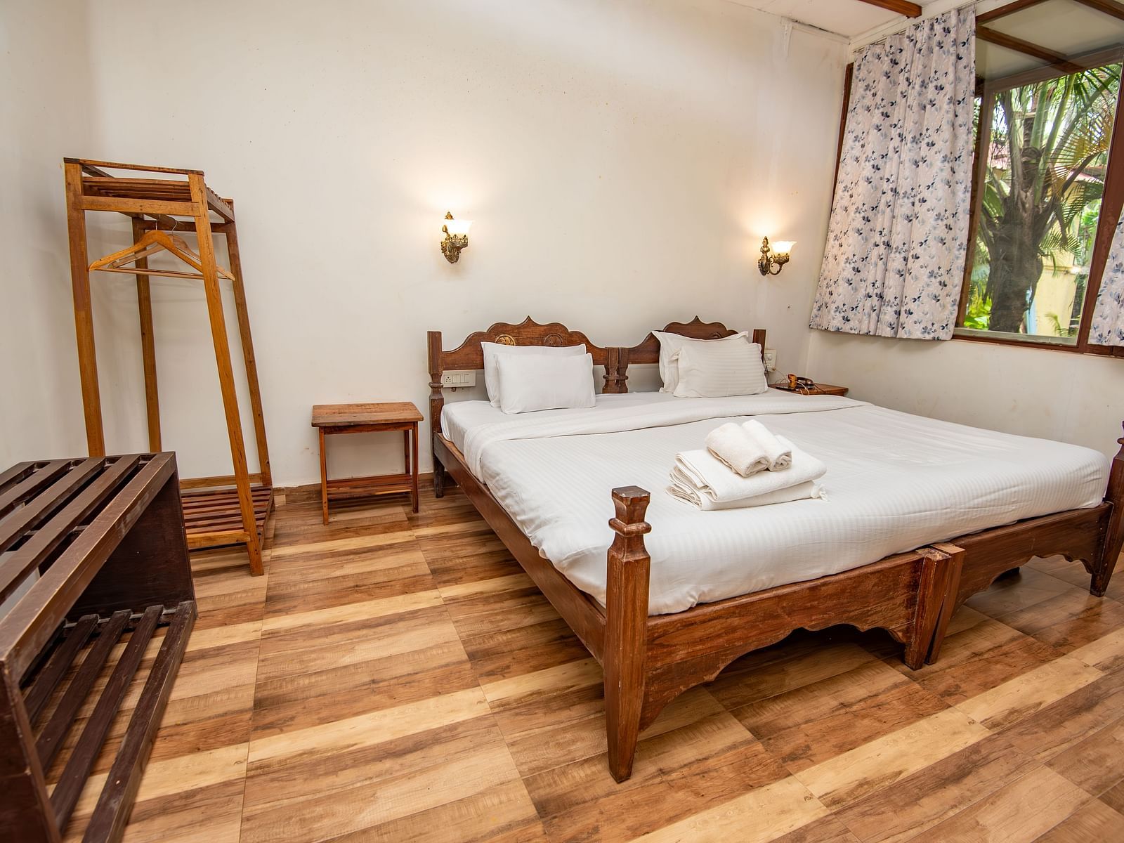 Neatly arranged bedroom with a bed, wooden accents, and a full-length mirror at De Soul Santé, Morjim.