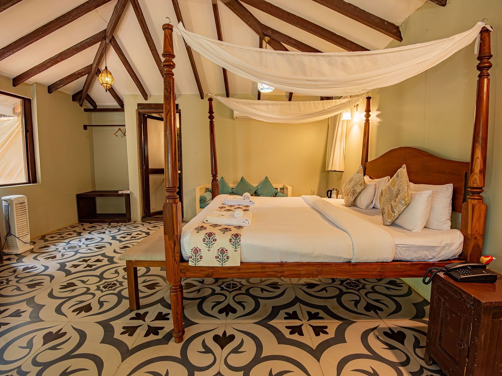 Elegant canopy bed in a spacious room with patterned flooring and warm lighting at De Soul Santé, Morjim.