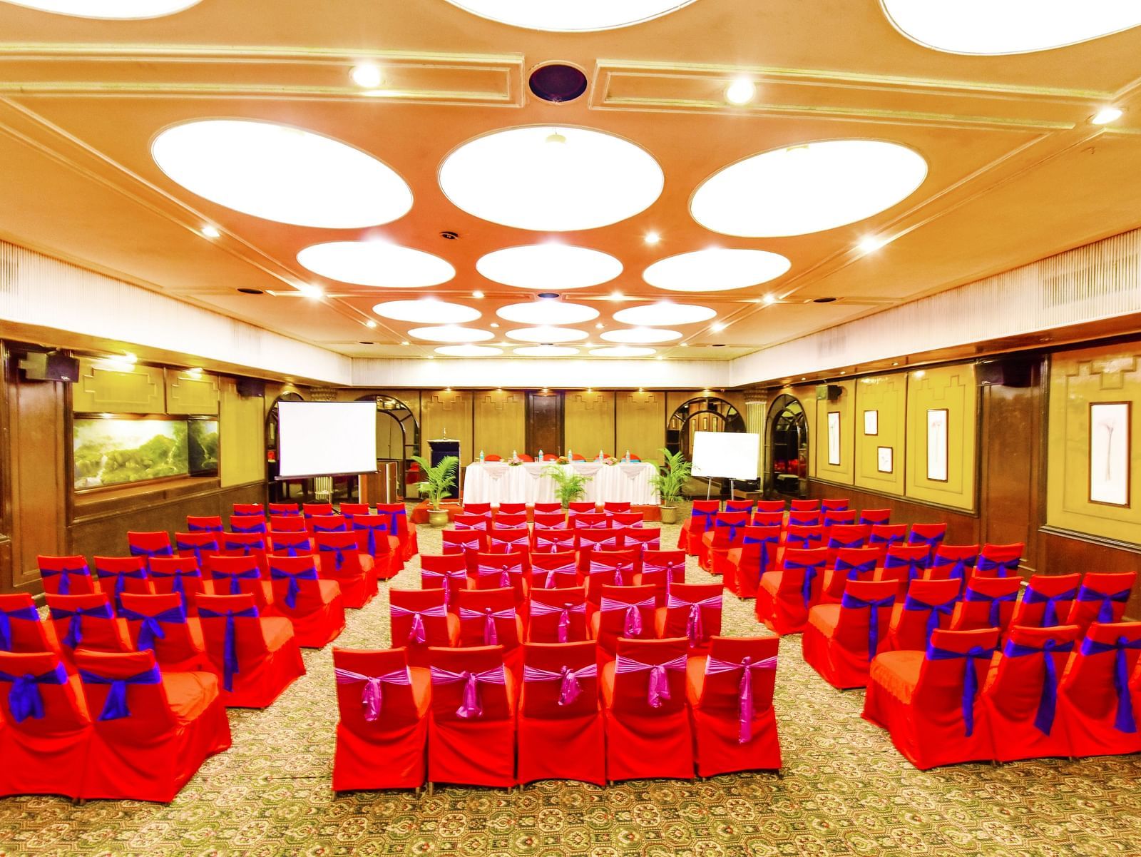 Image of a banquet hall with chairs arranged and a fancy lighting on the ceiling at Swosti Grand, Bhubaneswar