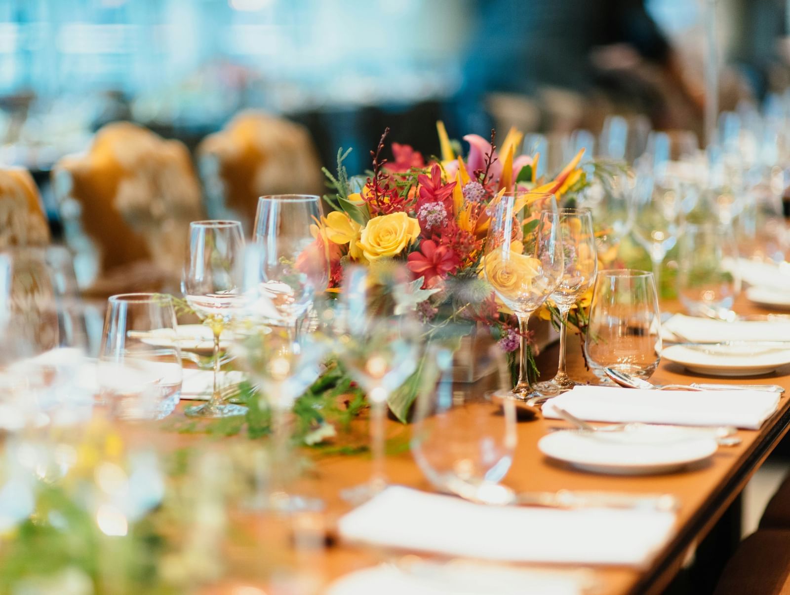  A beautifully decorated banquet-style table with floral arrangements, glasses, and dinnerware.