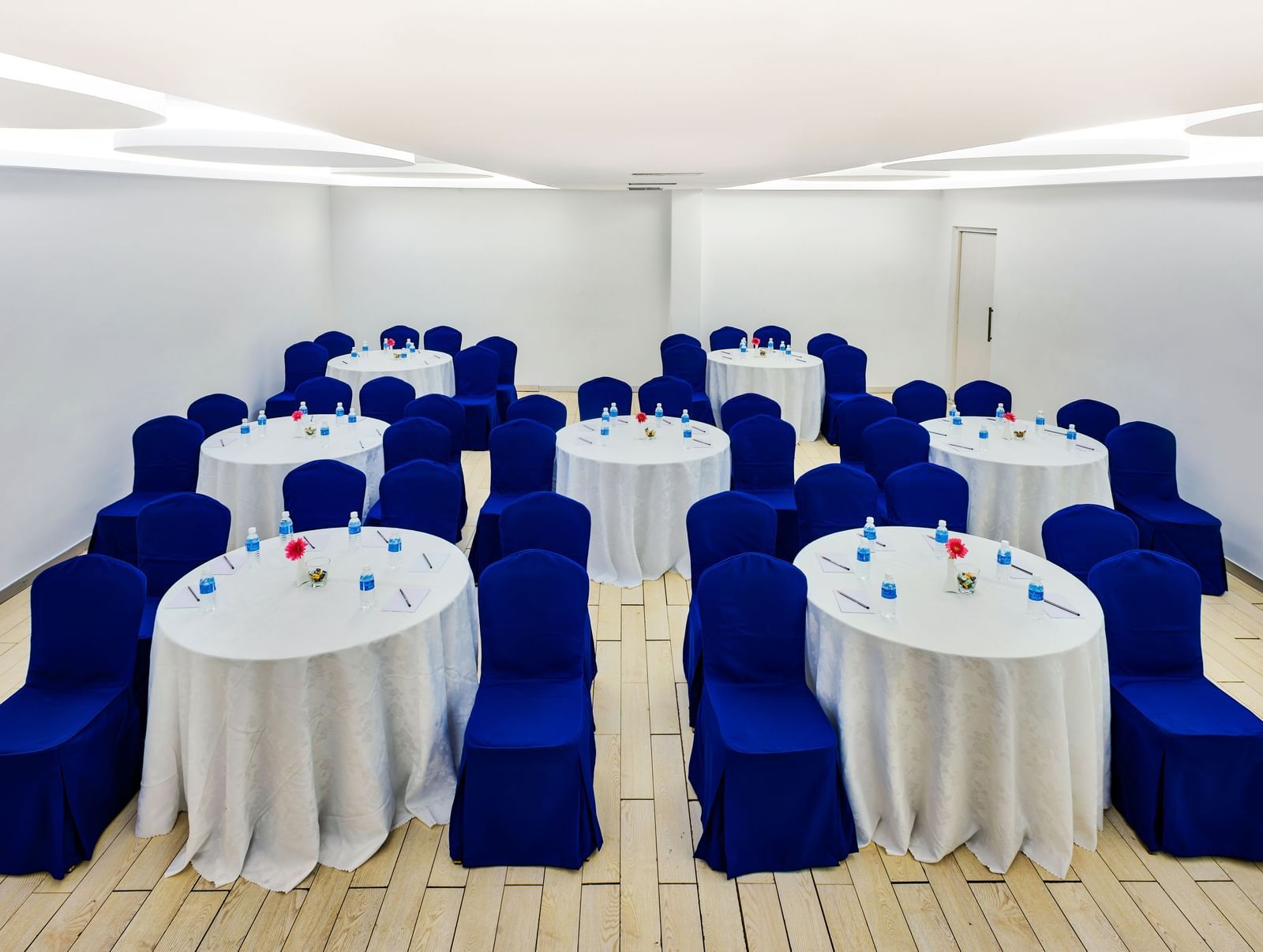 Rows of round banquet tables with white covers and blue chair sashes at Grande Bay Resort & Spa.