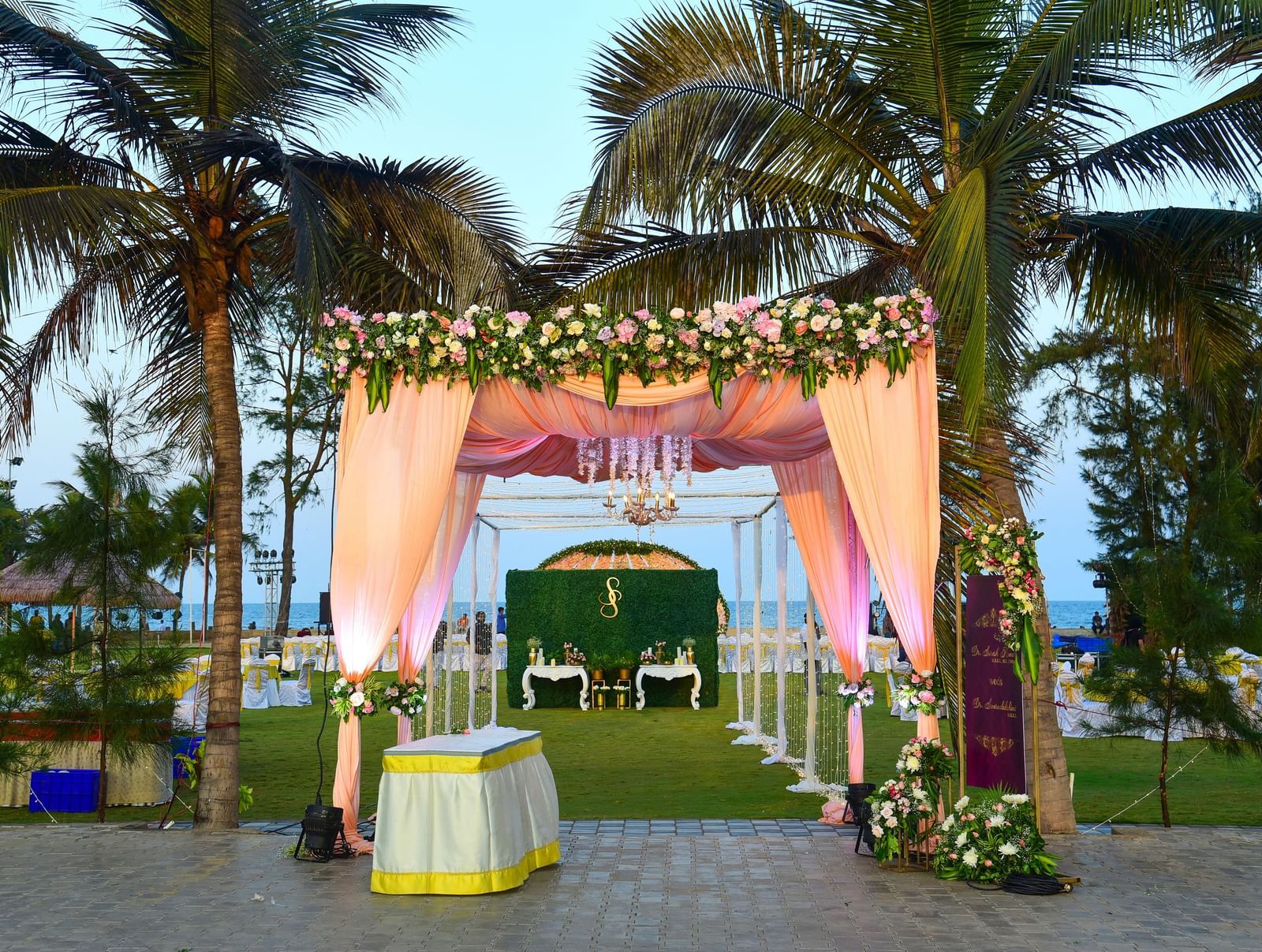 An outdoor wedding canopy with pink and yellow fabric and floral decorations, set on a green lawn with a white aisle | Horizon | Grand Bay Resort and Spa