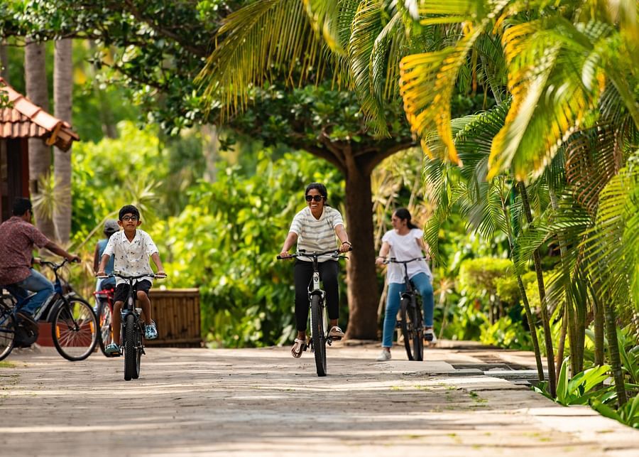 a group of kids cycling on a stone pathway with trees surrounding it and it is one of the best things to do in Pollachi - Ibex River Resort, Pollachi