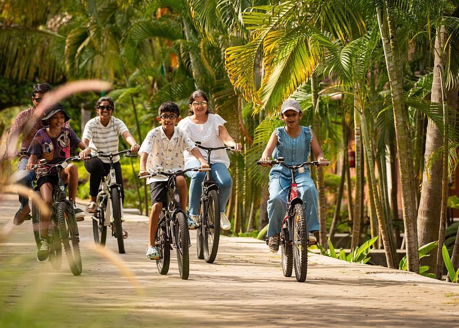 kids Cycling on a pathway next to coconut trees  - Ibex River Resort, Pollachi