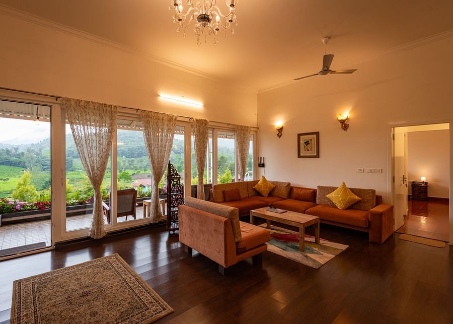 Main House Living Area with sofa and coffee table in the centre and floor to ceiling windows - Ibex Stays & Trails, Kotagiri