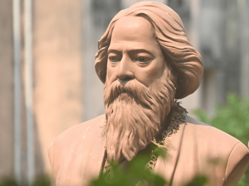 Stone portrait busts of Rabindranath Tagore and Kazi Nazrul Islam historic figures set amidst a green, leafy garden background