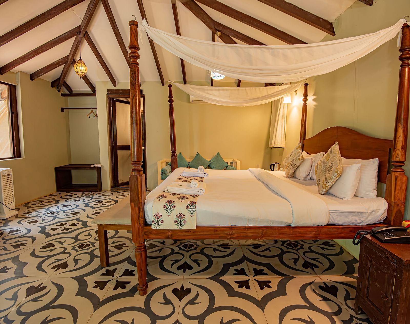 Elegant canopy bed in a spacious room with patterned flooring and warm lighting at De Soul Santé, Morjim.