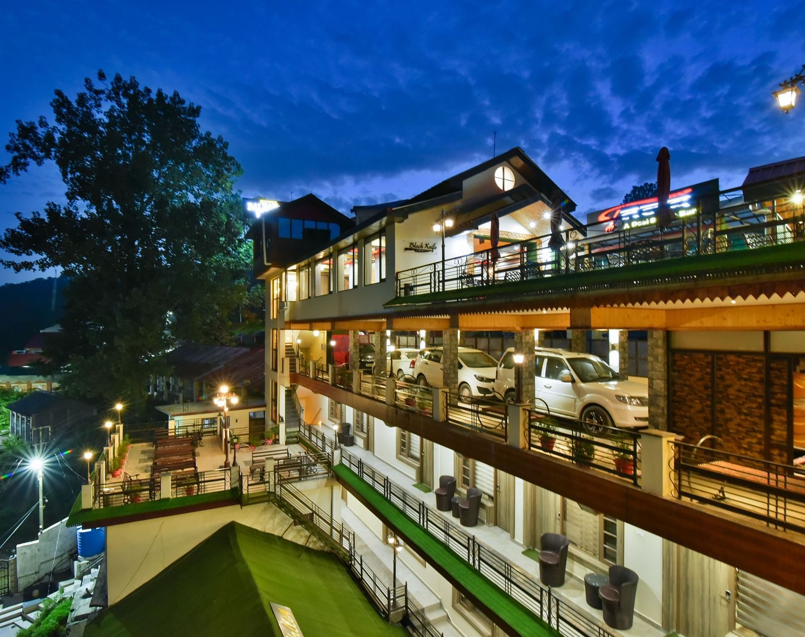 Facade image of DLS Dalhousie Valley Resort taken at night with warm lighting featuring parking area as well.