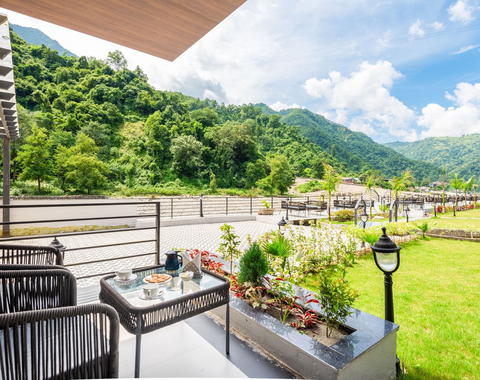 Closeup view of the balcony of Luxury Cottage at DLS Divine Resort and Spa featuring lush green garden area with chairs and tables