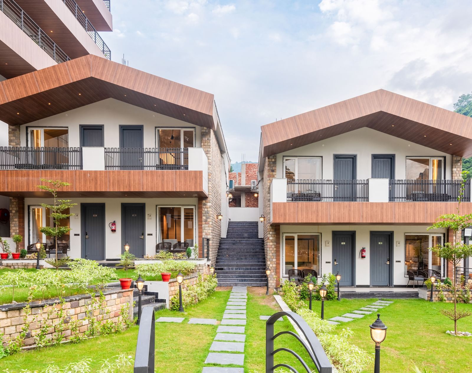 Facade of DLS Divine River Resort and Spa surrounded by lush green gardens and lamp posts.