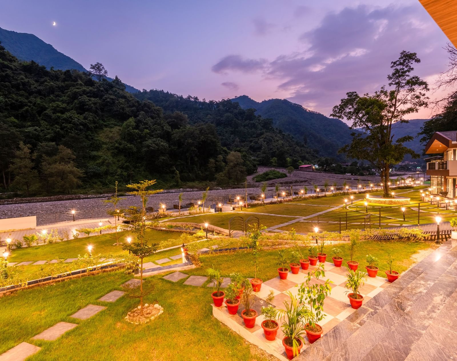 Garden area at DLS Divine River Resort and Spa featuring lush green grass and flower pots.