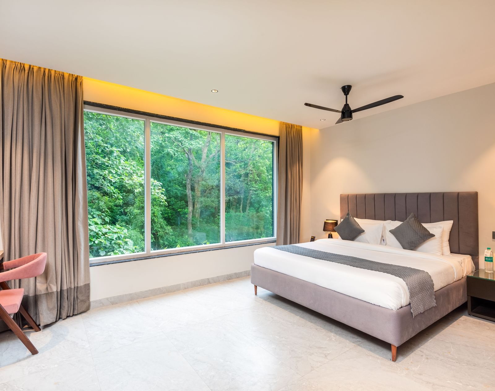 Overview of Deluxe Room at DLS Divine River Resort and  Spa featuring a  king bed , side table, chair and balcony with forest views.