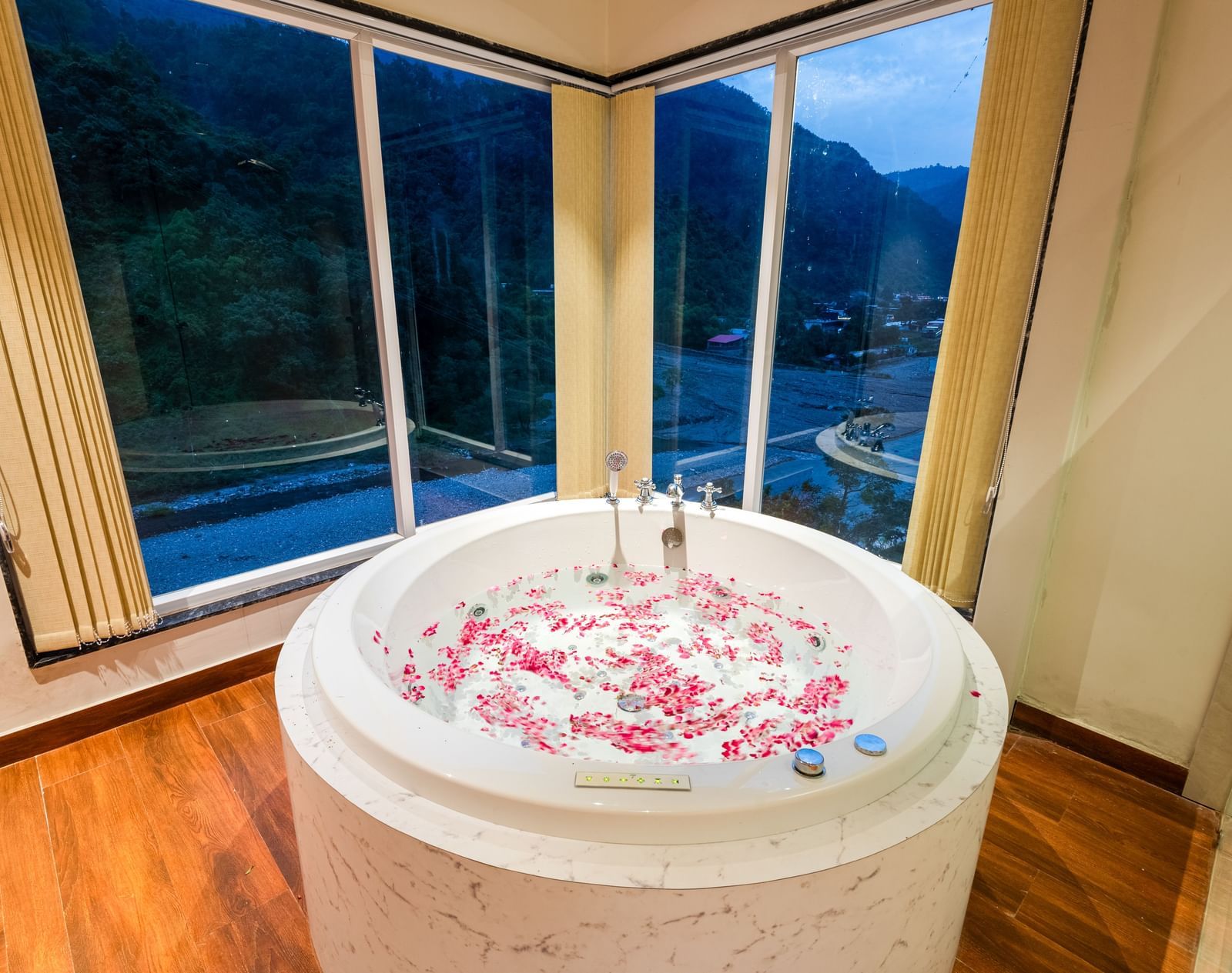 Jacuzzi at DLS Divine River Resort and Spa with flower petals floating in water and a huge window with serene views.