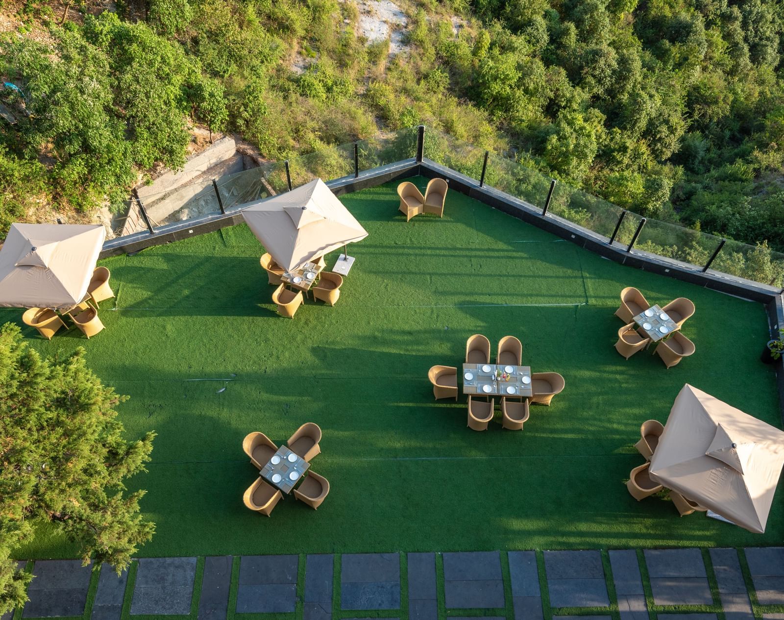 Aerial view of the lawn with comfortable seating surrounded by hills at Food and drinks placed on the table at DLS Highland Resort and Spa, Mussoorie.