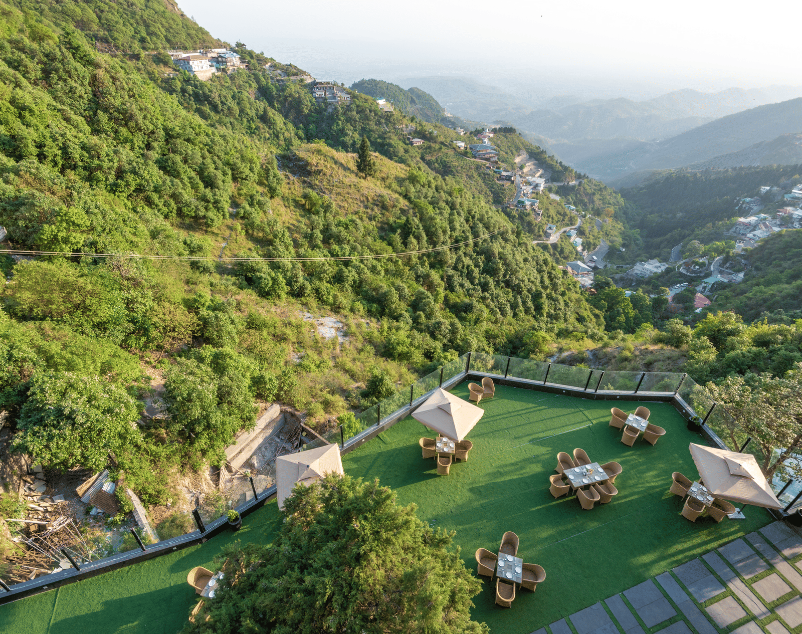 Aerial view of the lawn with comfortable seating surrounded by hills at Food and drinks placed on the table at DLS Highland Resort and Spa, Mussoorie.