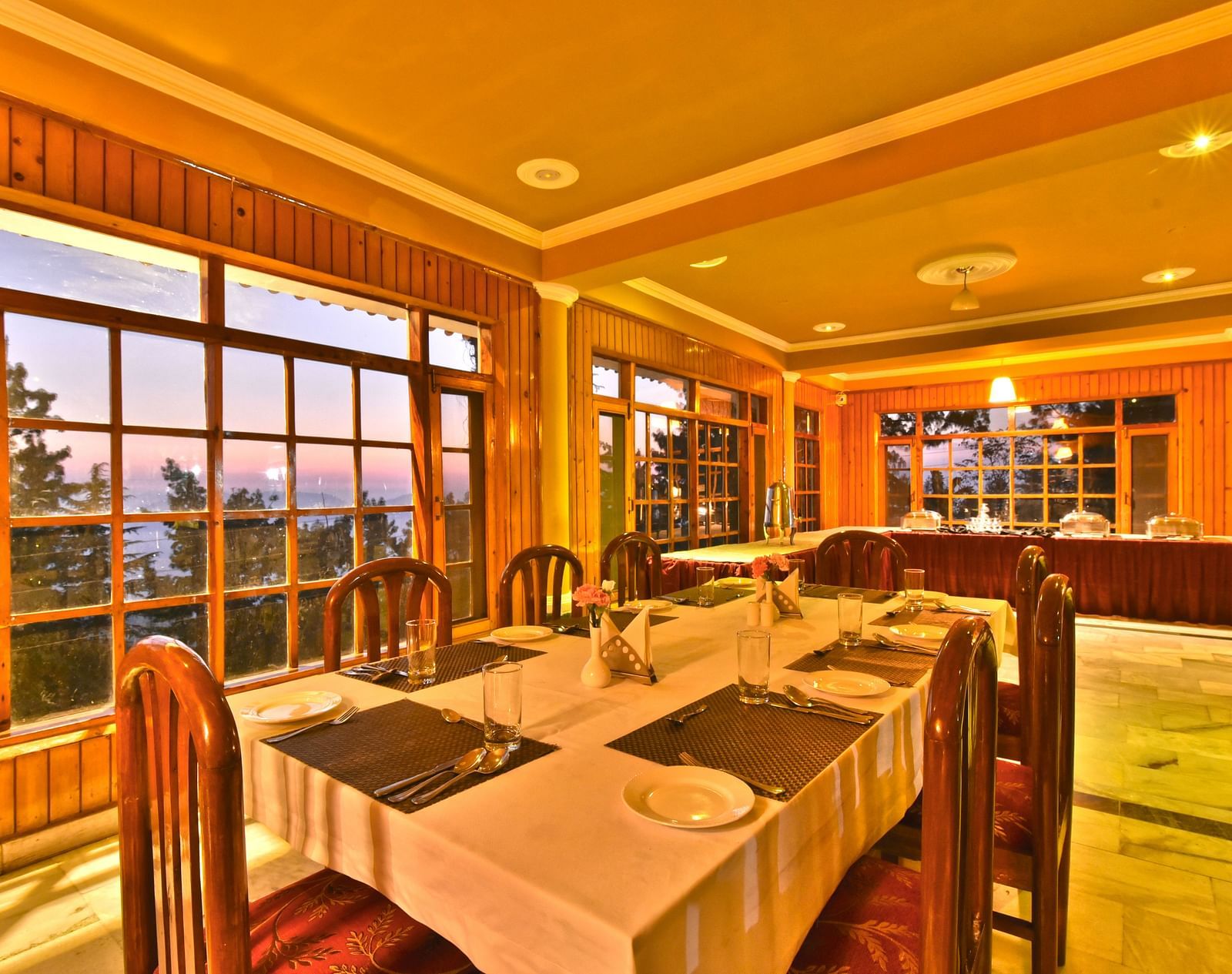 Restaurant with large windows offering scenic views at DLS Hillcrest Resort, Shimla.