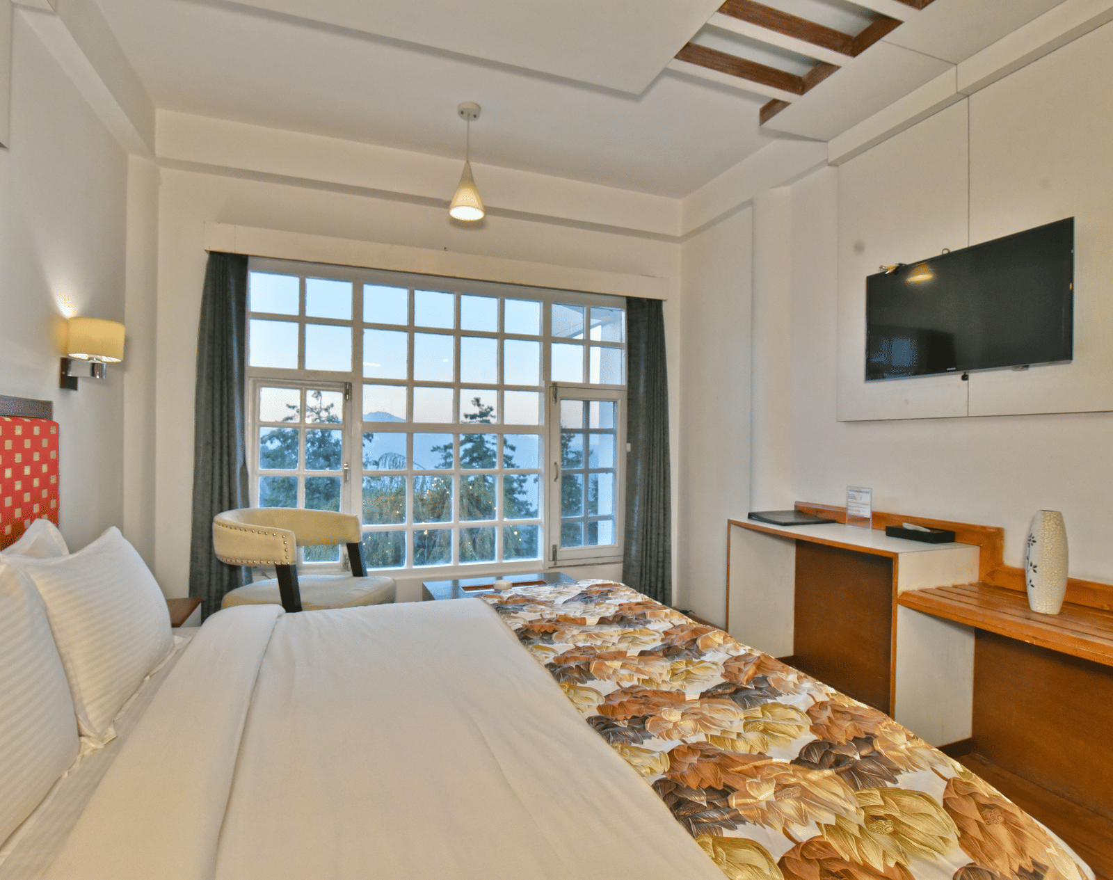 A bedroom with a wall-mounted television facing the bed at DLS Hillcrest Resort, one of the best places to stay in Mashobra.