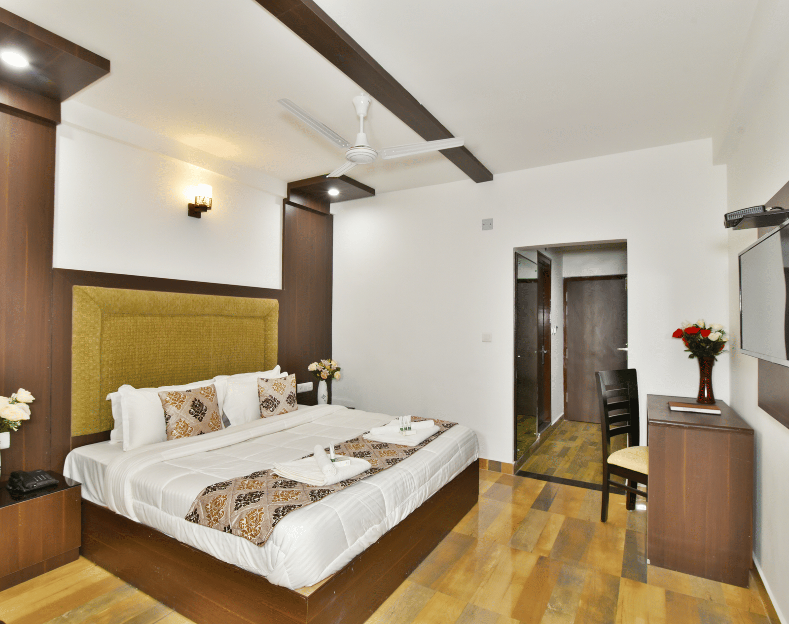 The spacious and well lit deluxe room that features a comfortable bed, a work desk, and a modern aesthetic - DLS Kapoor Resort, Manali.