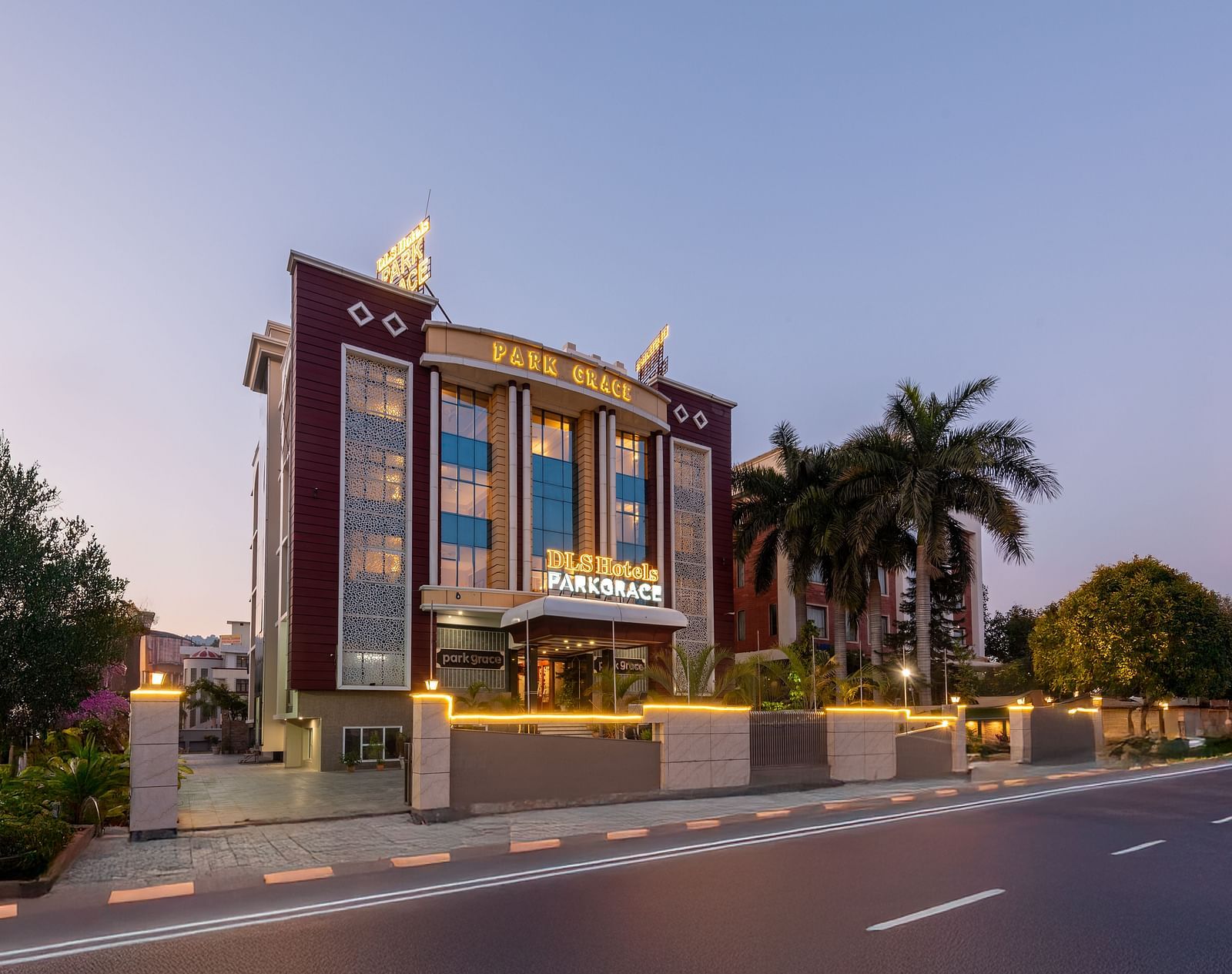 Exterior view of DLS Park Grace, Haridwar featuring well infrastructure, warm lighting, main road and the green surroundings.