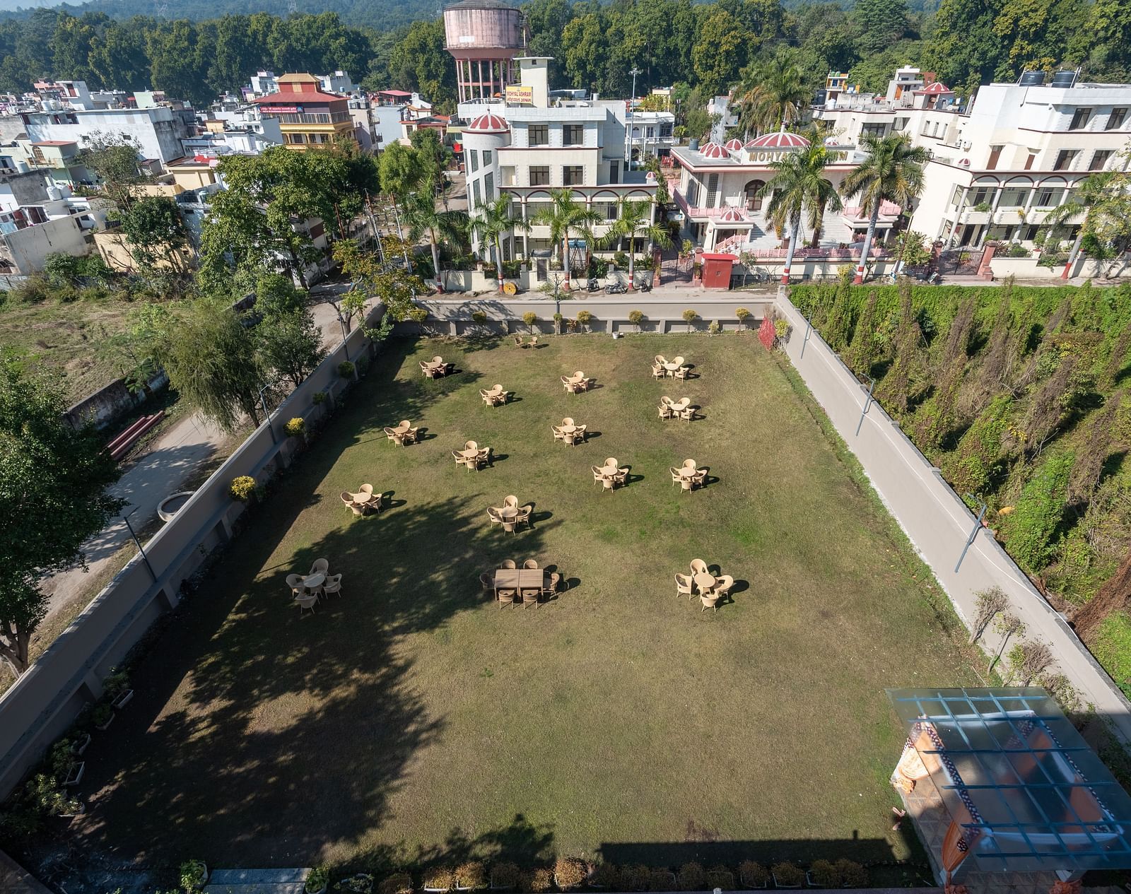 Lush green lawn encircled by tall trees at DLS Park Grace, Haridwar.
