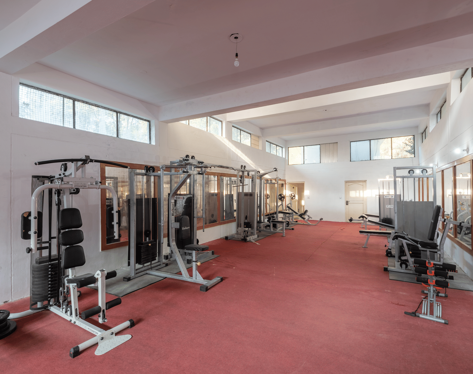 A well-equipped gym at DLS Tehri Club Resort with a variety of cardio and strength training equipment.