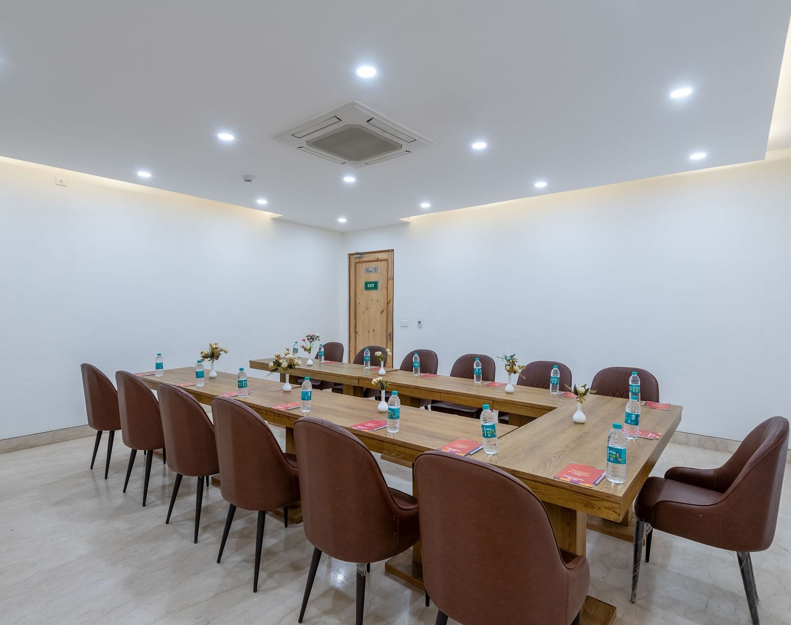 Side view of a conference room with multiple chairs, an air conditioner, and water bottles placed on the table at DLS The Classio