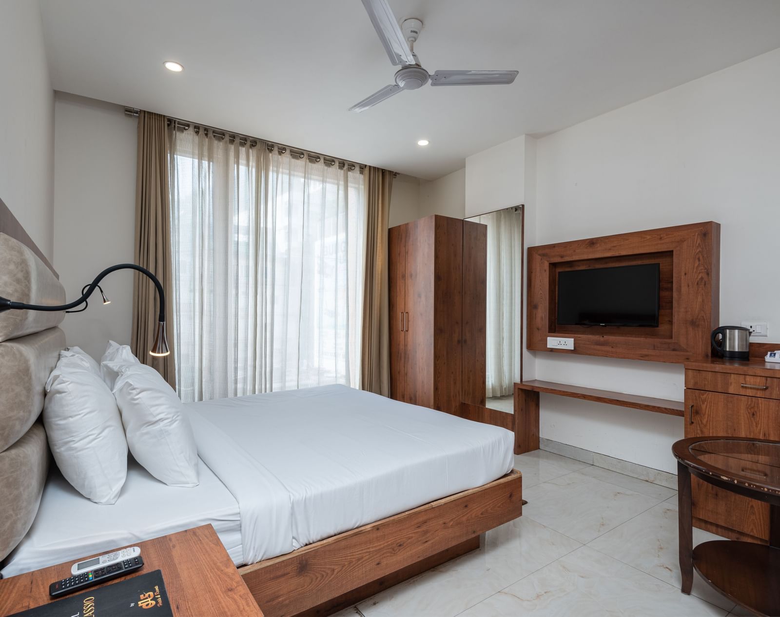 Side view of a Deluxe Room featuring a TV mounted on the wall and a ceiling fan overhead, at DLS The Classio