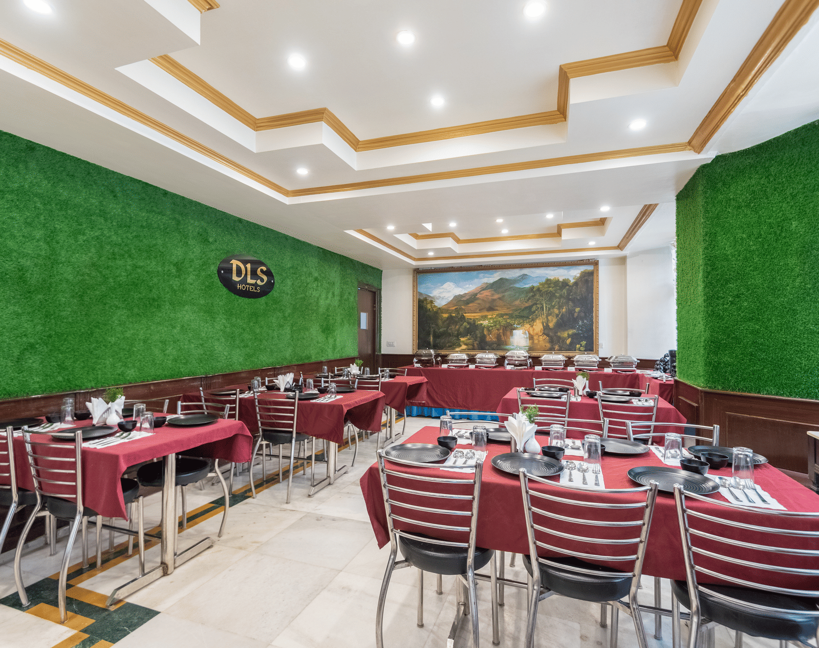 A spacious restaurant with a green wall, red tablecloths, and a scenic mural on one wall | DLS The Pearl
