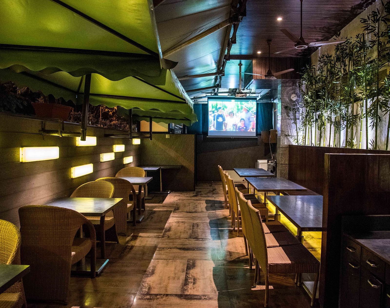 Modern restaurant featuring wooden chairs, tables, and a wall with plants hanging as decoration at Oriental Aster, Mumbai.