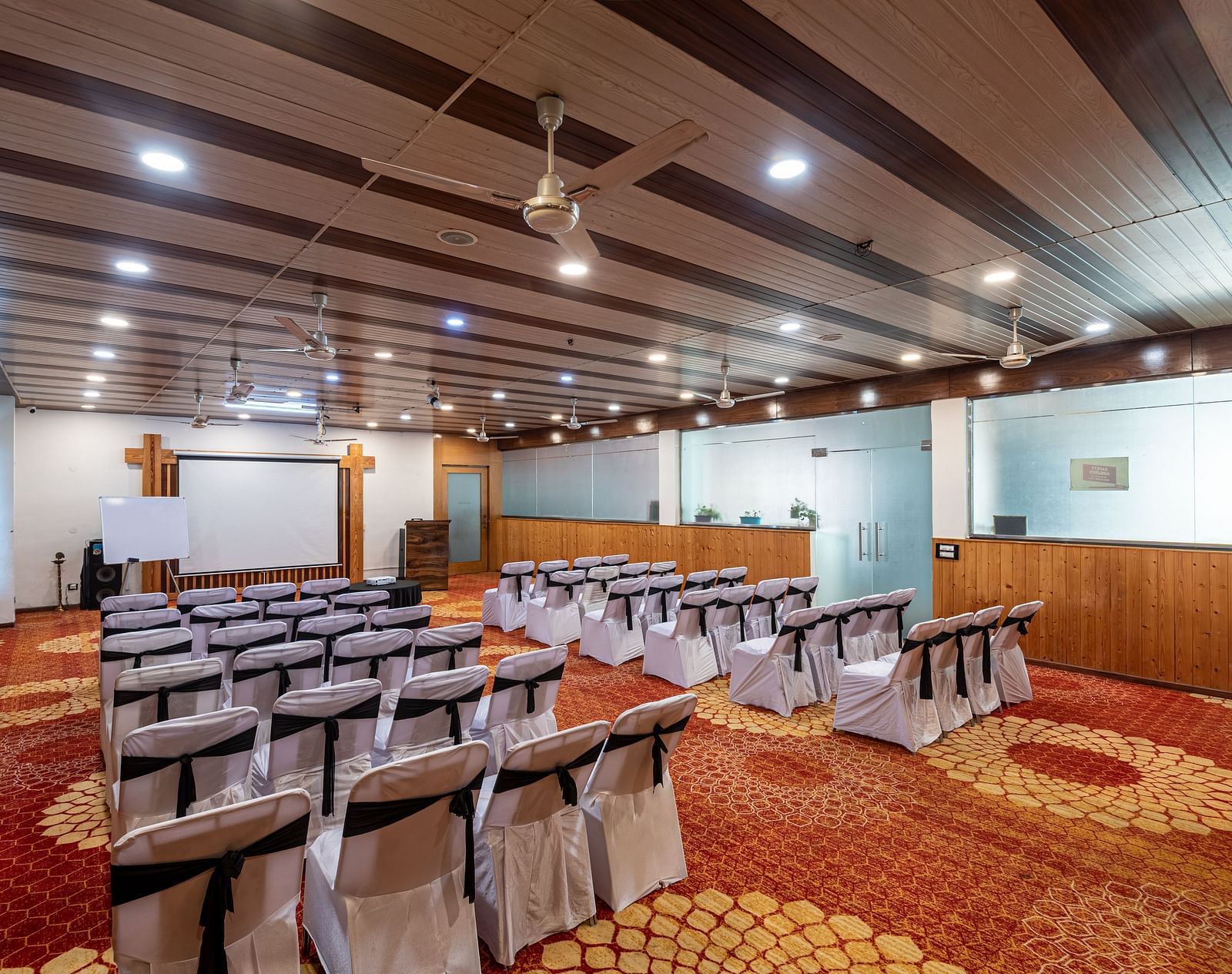 Spacious banquet hall at Regenta Inn DLS, Rishikesh with chairs aligned neatly and a white screen.