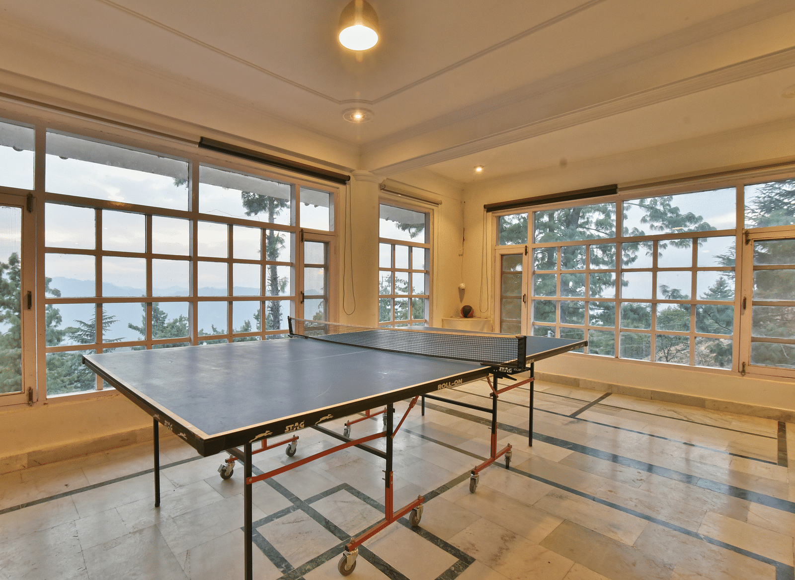 A spacious table tennis area with multiple windows welcoming plenty of natural light at DLS Hillcrest Resort, Shimla.