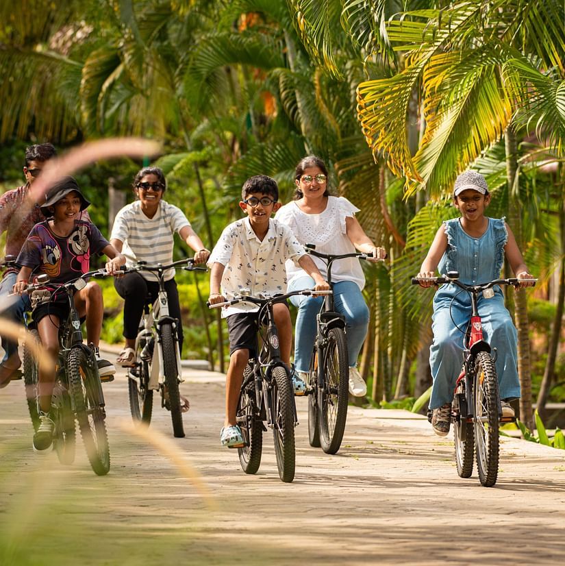 kids Cycling on a pathway next to coconut trees  - Ibex River Resort, Pollachi